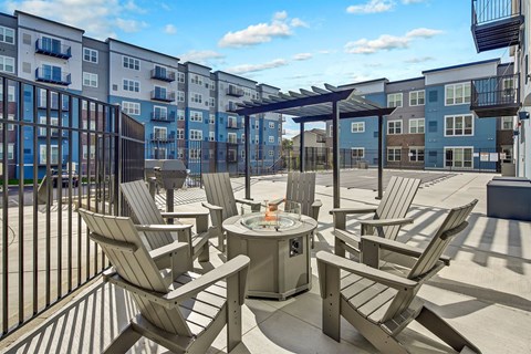 an outdoor patio with chairs and a fire pit and an apartment building