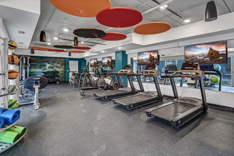 a gym with treadmills and other exercise equipment in a building with colorful ceilings