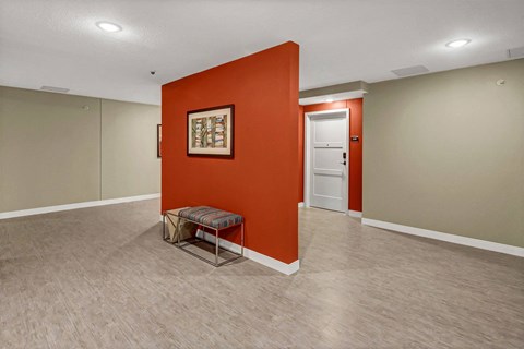 an empty room with an orange wall and a chair