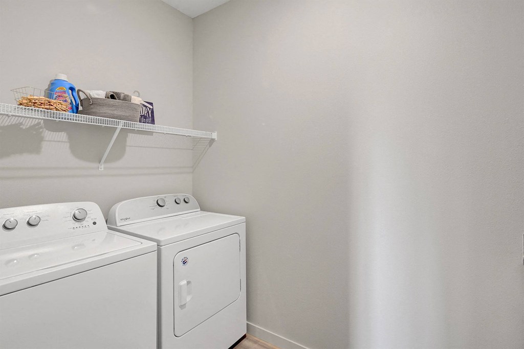 a white washer and dryer in a laundry room with a shelf above it