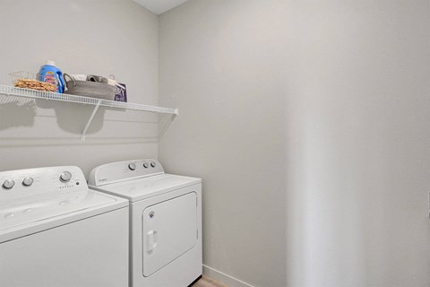 a white washer and dryer in a laundry room with a shelf above it
