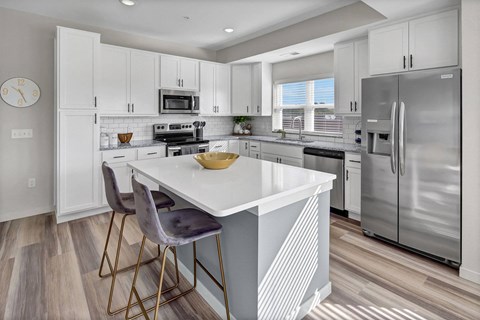 a white kitchen with stainless steel appliances and a white counter top