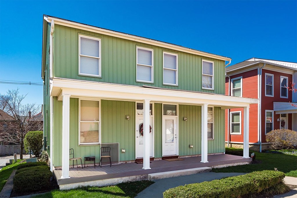 A green house with a white door and windows.