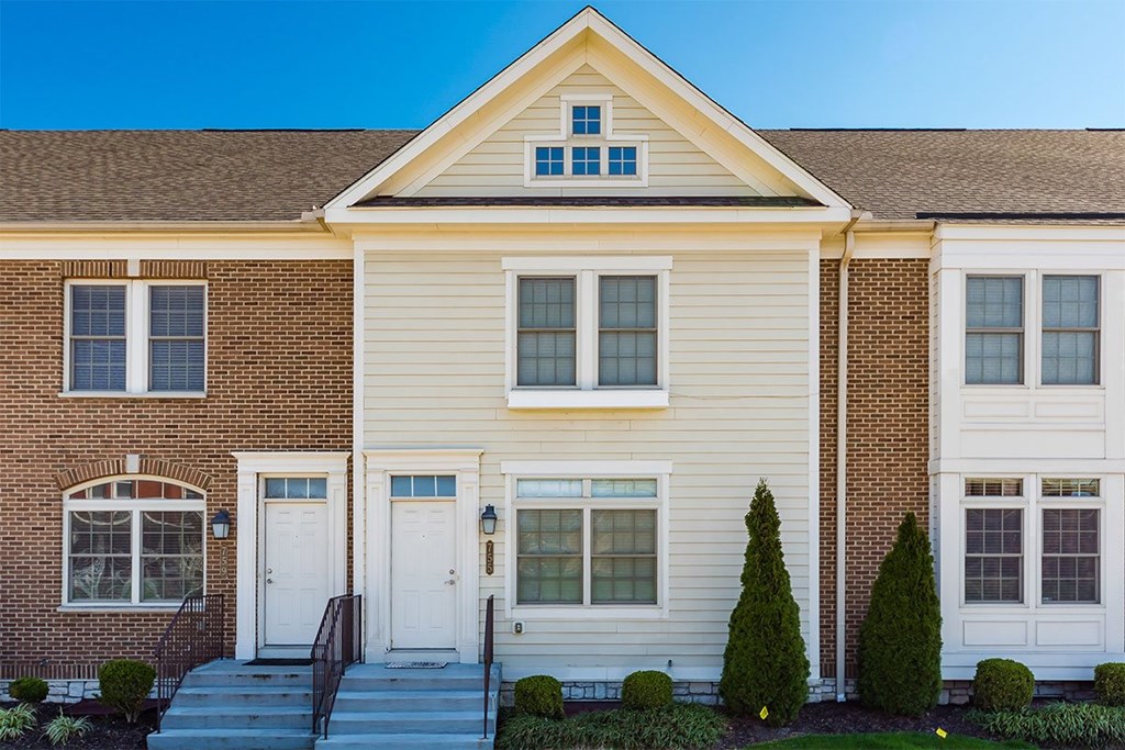 A two-story house with a white front door and a small porch.