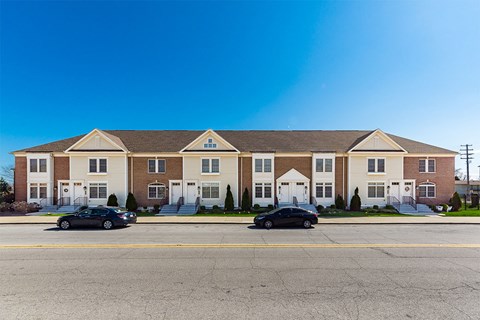 A large apartment building with two cars parked in front.