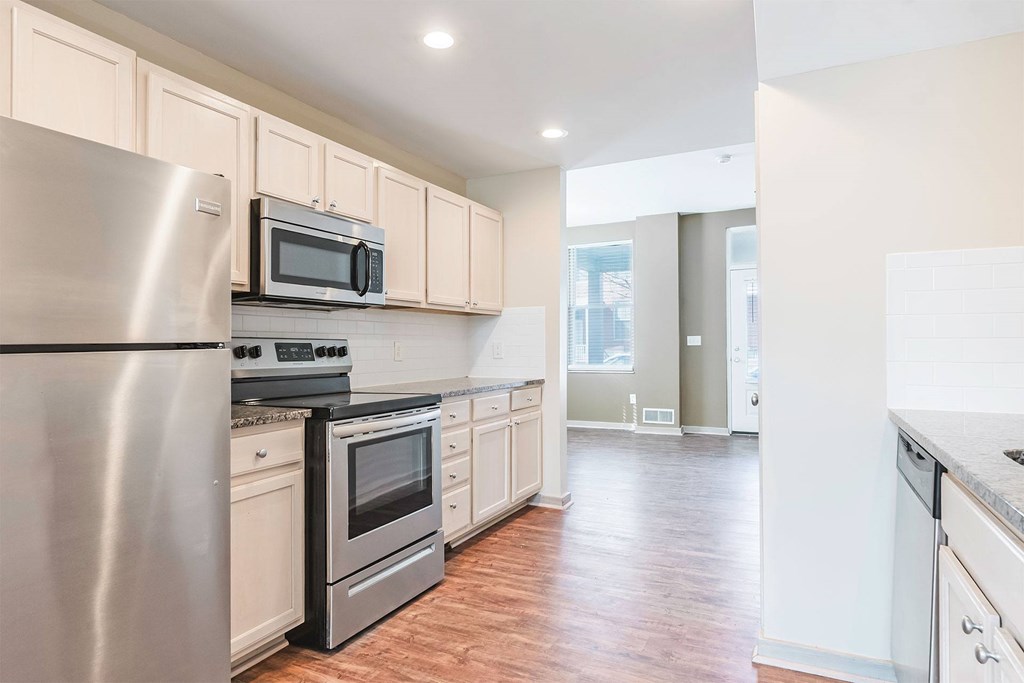 A kitchen with a stainless steel refrigerator, microwave, oven, and dishwasher.