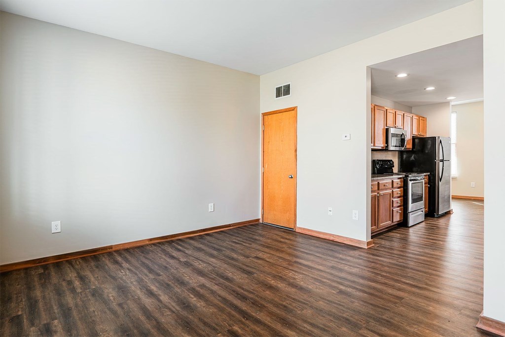 A kitchen with a refrigerator, microwave, and oven is visible through the doorway.