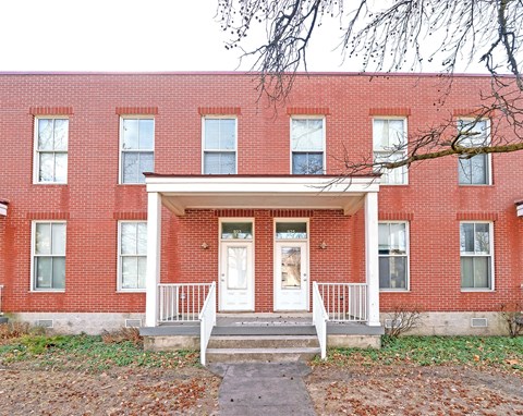A red brick building with a white door and windows.