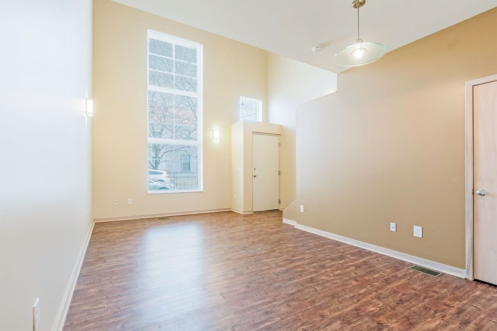 A room with wooden floors and a window showing a view of trees and buildings outside.
