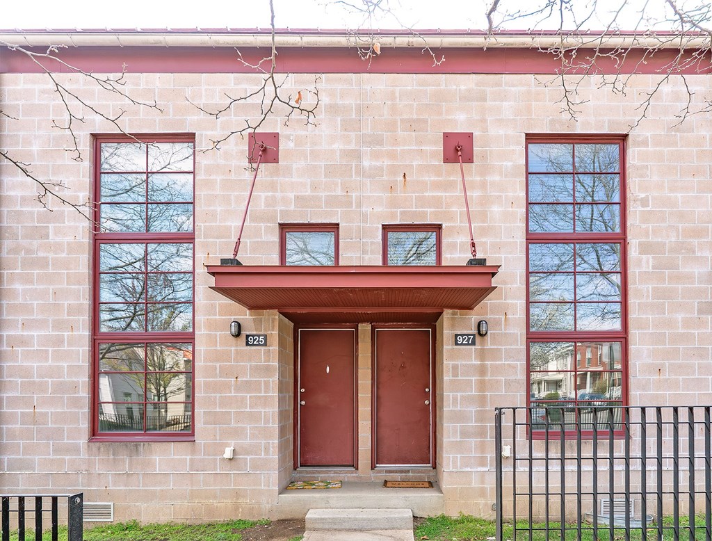 A red door is on the front of a brick building.