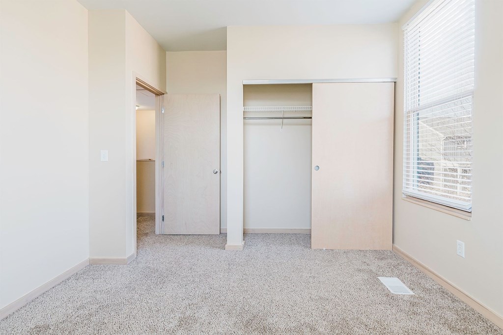 A room with a carpeted floor and a window with blinds.