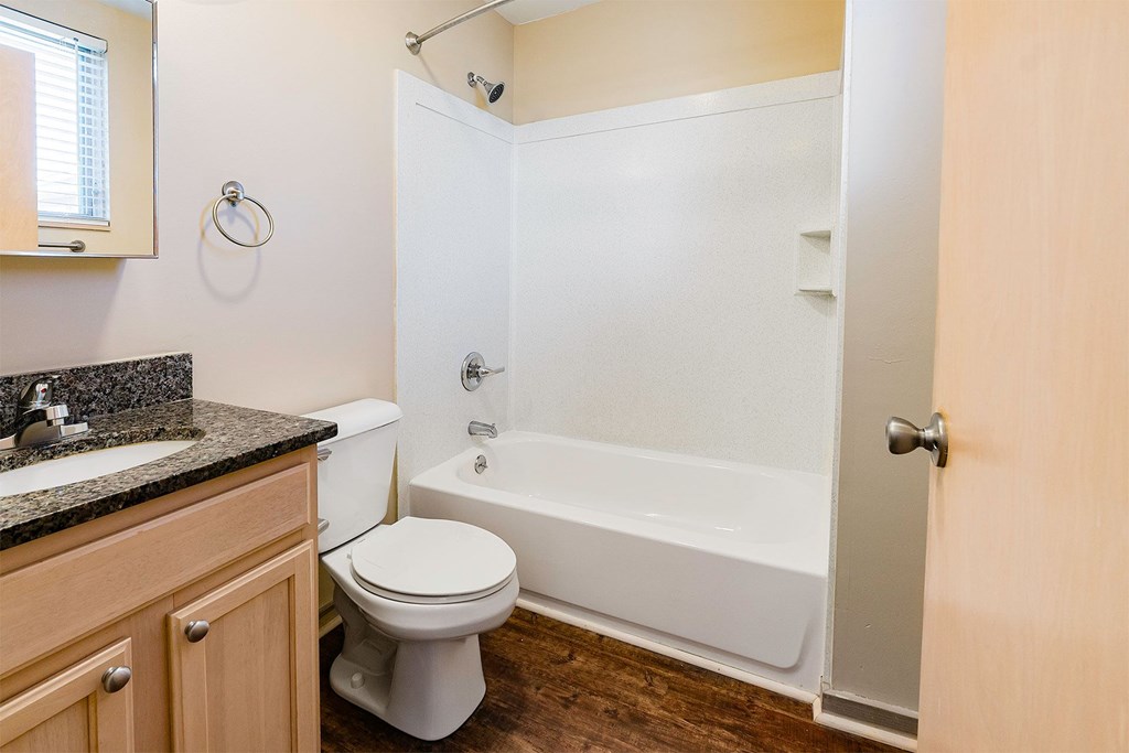 A white toilet sits next to a white bathtub in a bathroom.