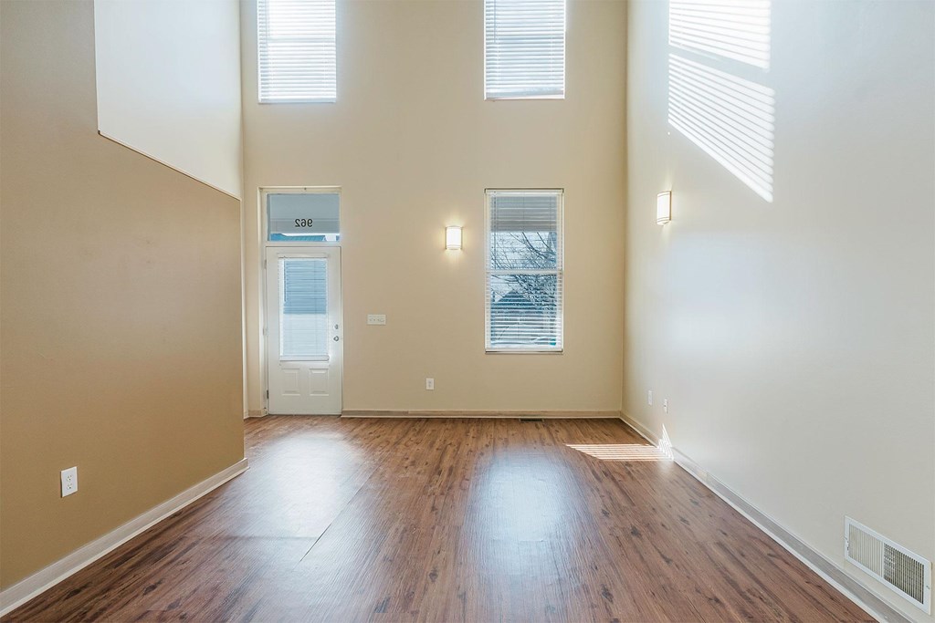 A room with wooden floors and a door leading to another room.