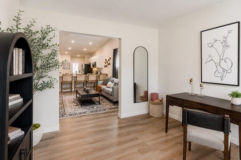 A living room with a black bookcase, a coffee table, a couch, a chair, and a painting on the wall.