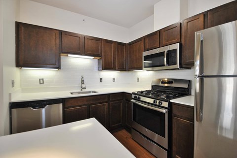 A kitchen with dark wood cabinets and stainless steel appliances.