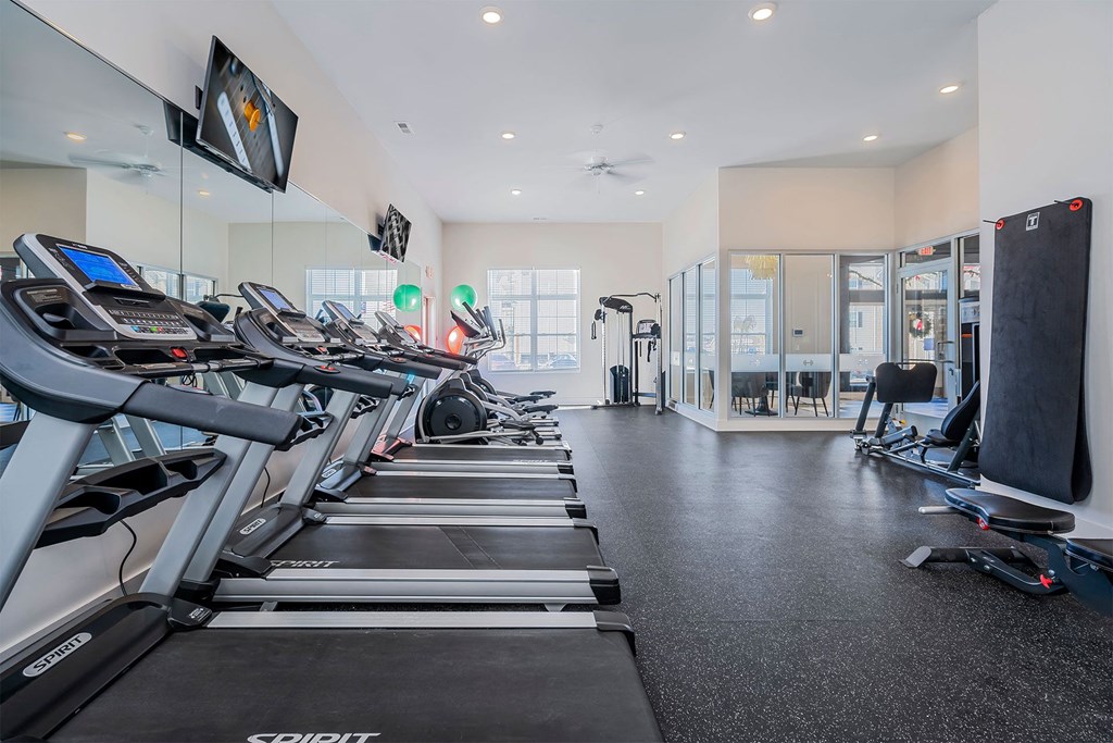 A gym with treadmills and a television on the wall.