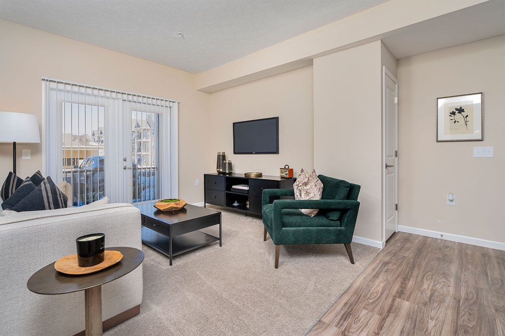 A living room with a green armchair, a black coffee table, and a flat screen TV mounted on the wall.