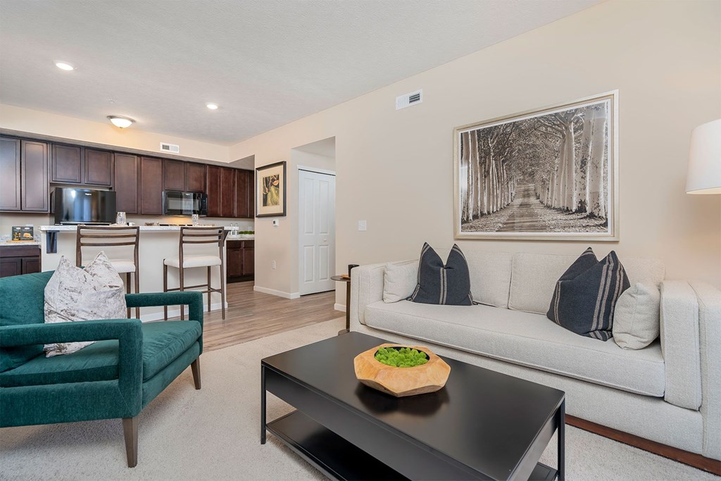 A living room with a green chair, a black coffee table, and a white couch with a pillow.