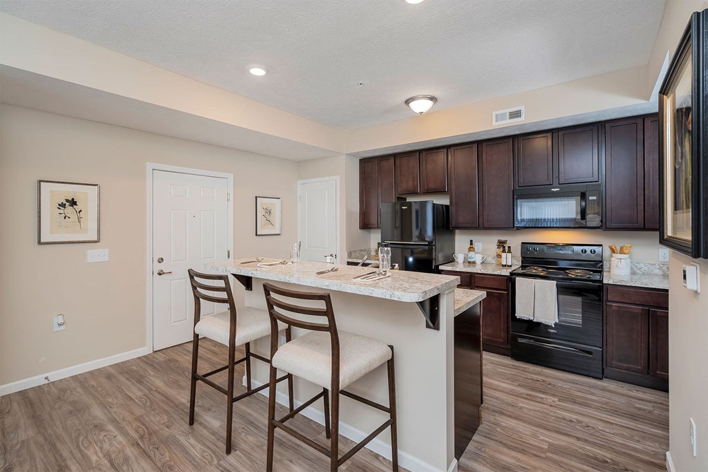 A kitchen with a white island and dark brown cabinets.