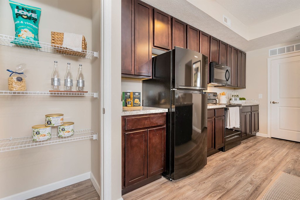 A kitchen with a black refrigerator and wooden cabinets.