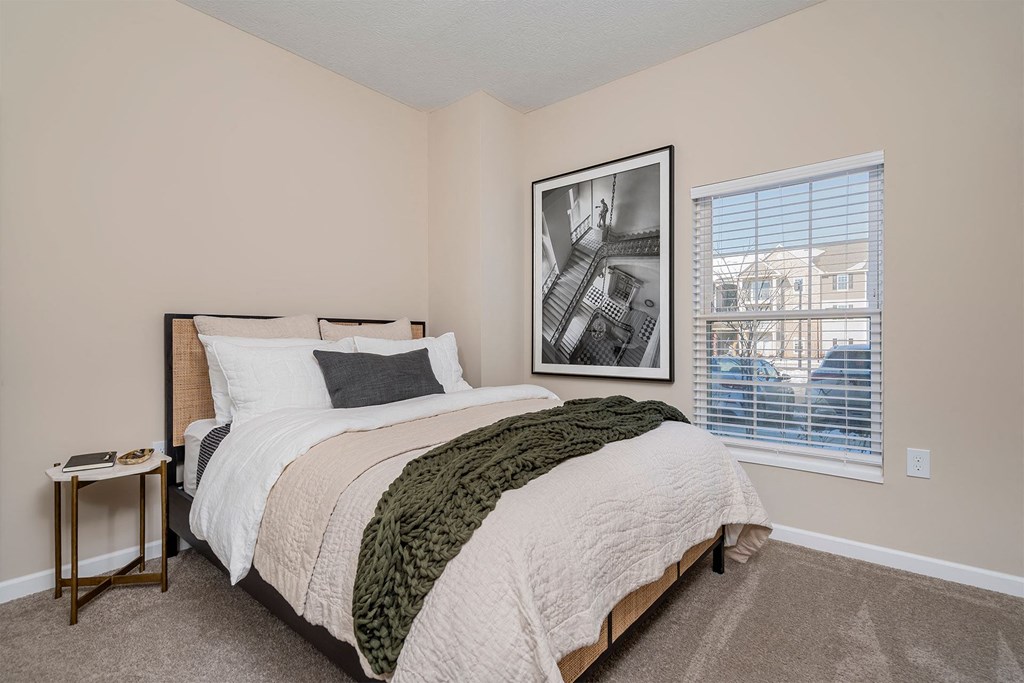 A bedroom with a large bed and a picture on the wall.