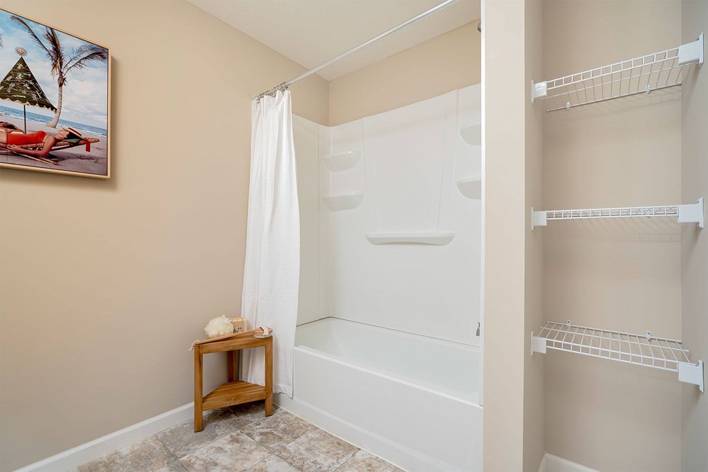 A bathroom with a white tub and shelves.