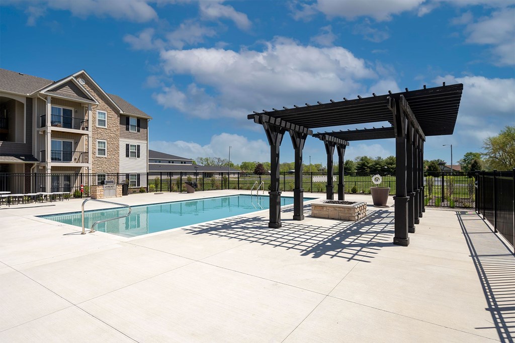 A pool area with a pavilion and a building in the background.
