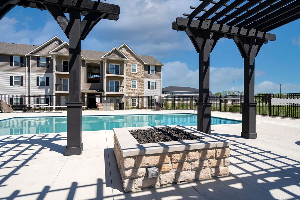 A pool area with a black pergola and a stone bench.