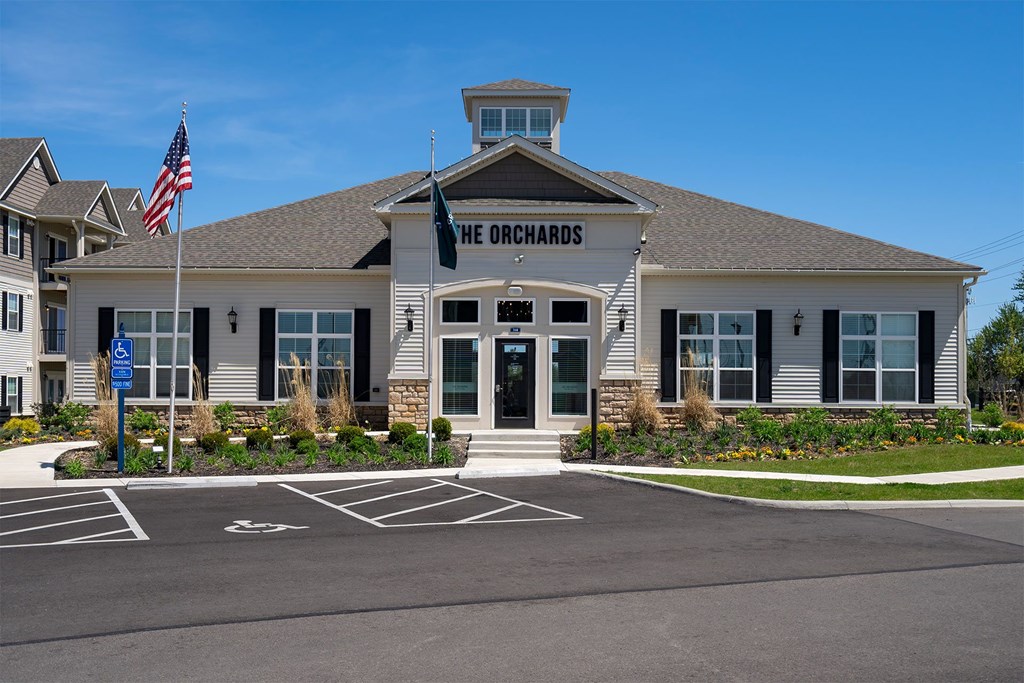 The Orchards building has a flag on top and a parking lot in front.