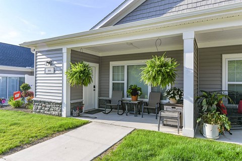 A house with a grey siding and a white porch.