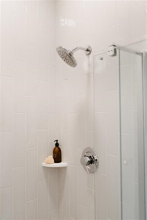 a white bathroom with a shower and a small shelf