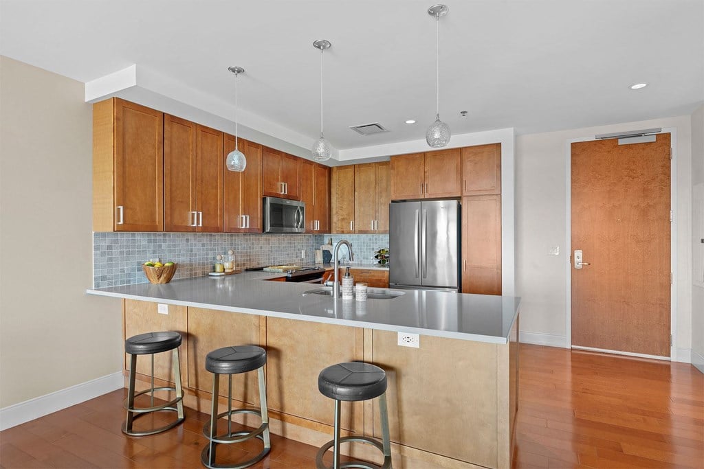 A kitchen with wooden cabinets and a stainless steel refrigerator.