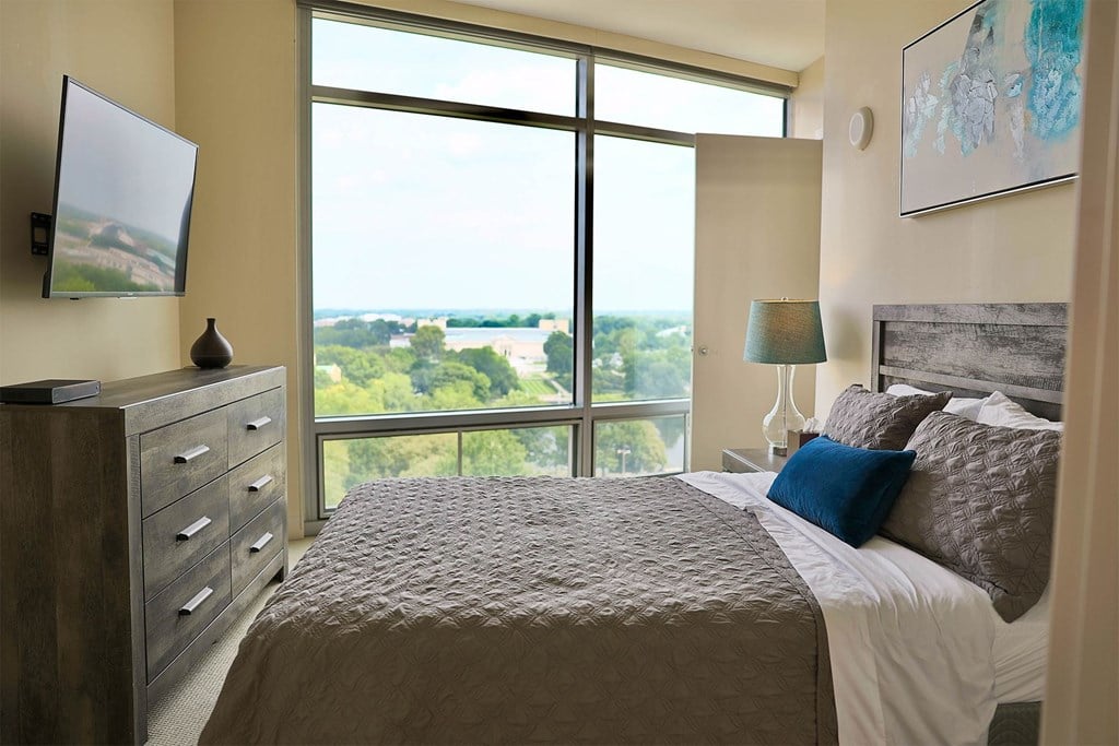 A bedroom with a large bed and a view of the outdoors through the window.
