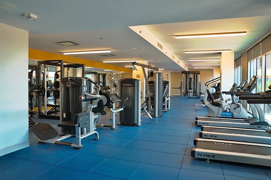 A gym with a variety of equipment including treadmills, weights, and exercise machines.
