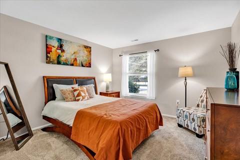 A bedroom with a large bed and a painting on the wall.