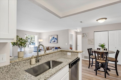 A kitchen with a granite countertop and a dining table with chairs.