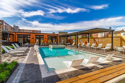 A pool area with sun loungers and a building in the background.