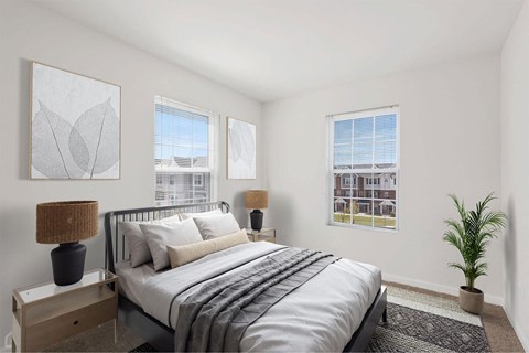 A bedroom with a bed, nightstand, and two windows.