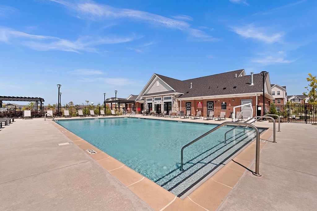 A large outdoor swimming pool with a glass barrier and a building in the background.