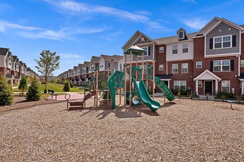 A playground with a green slide in front of apartment buildings.