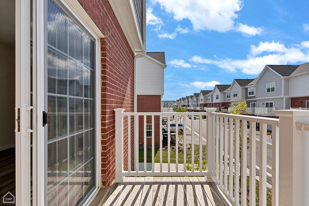 A balcony with a glass door leading to a brick building.