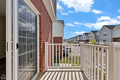 A balcony with a glass door leading to a brick building.