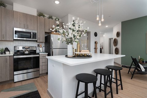 an open kitchen with a large island with three stools