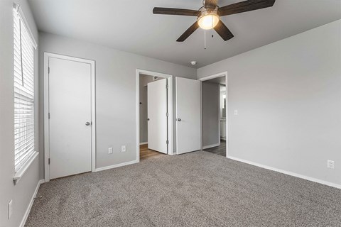 A room with a ceiling fan and carpeted floor.