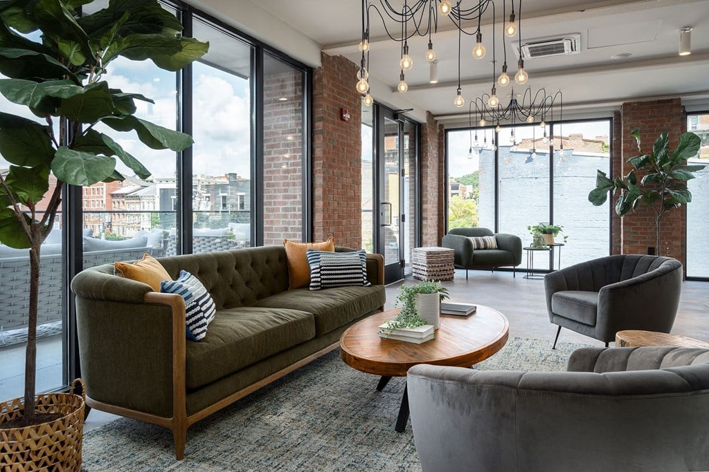 a living room with couches and chairs and large windows