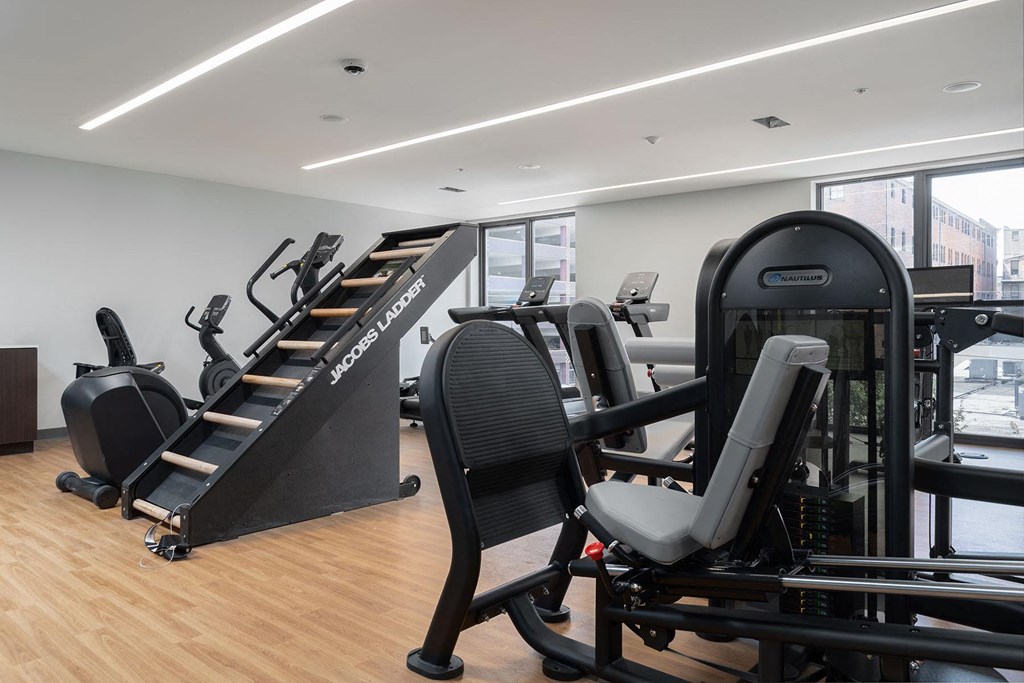 a gym with various exercise equipment on a wooden floor