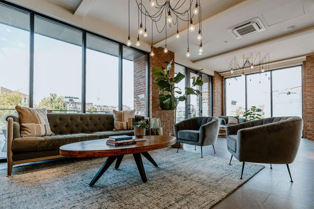 a living room with couches and chairs and large windows