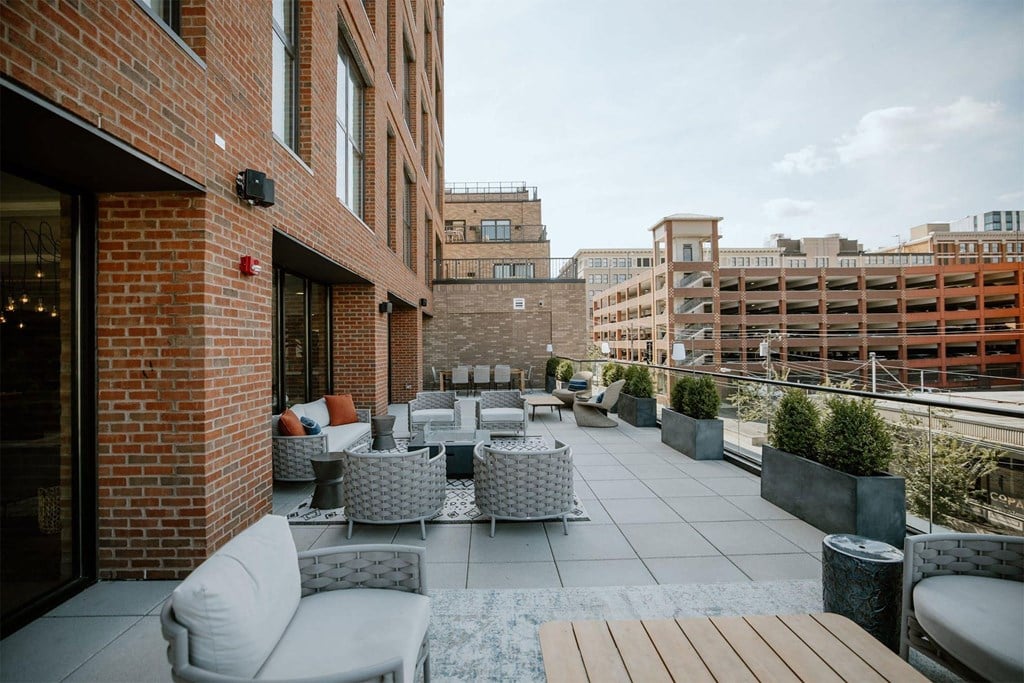 a rooftop patio with tables and chairs and a city in the background