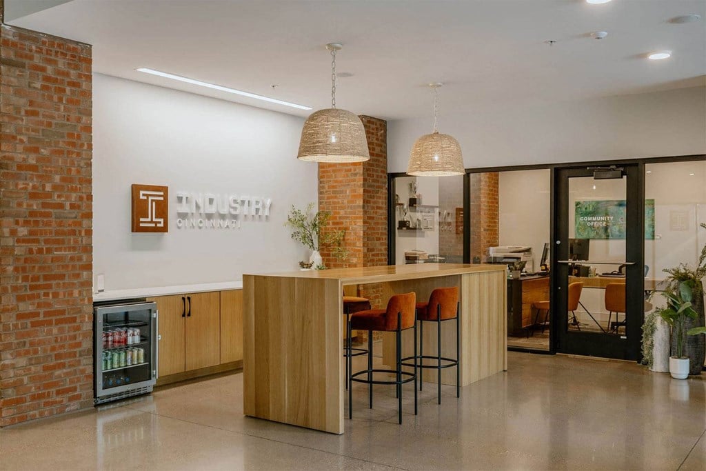 a kitchen with a counter and chairs in front of a brick wall
