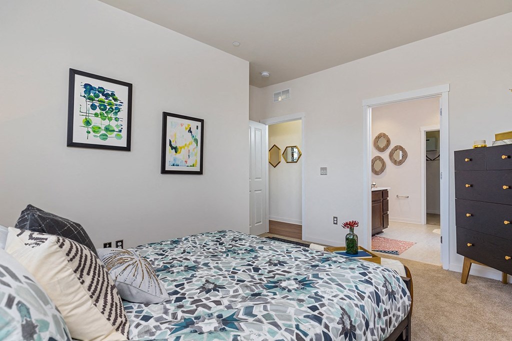 a bedroom with a bed and a dresser and a bathroom